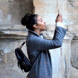 woman in blue plaid coat holding up her phone